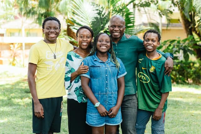 Dr. Malaba with his family - a happy family of five standing together outdoors